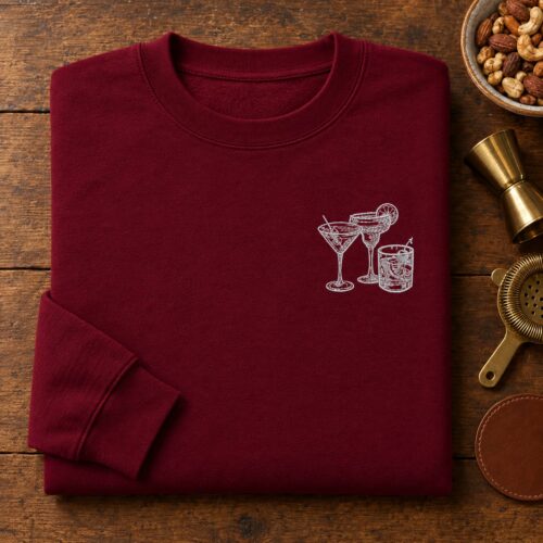 Diseño de bordado "Cocktail Hour Sketch" bordado como logotipo en el lado izquierdo del pecho de una sudadera de cuello redondo.